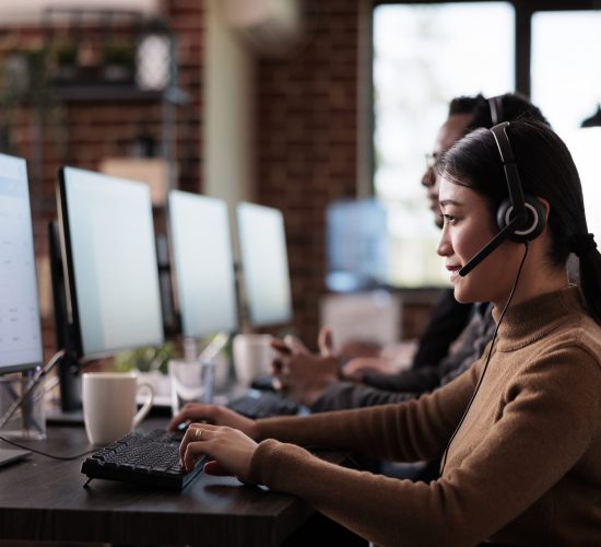 Paralyzed asian employee working at call center reception Paralyzed asian employee working at call center reception in disability friendly office. Female operator wheelchair user with impairment giving assistance on customer service helpline.